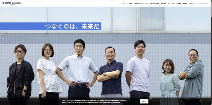 システックの採用サイト。屋外に社員7名が服装も立ち方もばらばらのまま横一列に並び、上に青い帯で「つなぐのは、未来だ」と入る